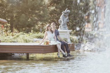 Yeni evliler göldeki iskelede oturuyorlar. Aşıklar yan görünümü güzel çift