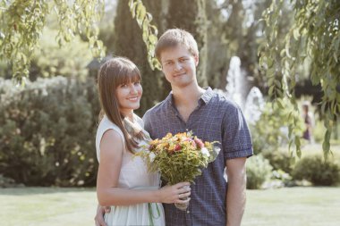 Bir çift aşık, bir aşk hikayesi, bir erkek ve bir kız, ellerinde buket olan bir gelin ve damat. Parkta bir yaz gününde mutlu çift