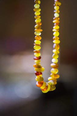 Güneşte parlayan doğal kehribar boncuklar yakın. Karanlık bir arka plan üzerinde gerçek taşlar el yapımı hediyelik eşya, seçici odak