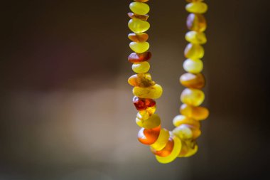 Güneşte parlayan doğal kehribar boncuklar yakın. Karanlık bir arka plan üzerinde gerçek taşlar el yapımı hediyelik eşya, seçici odak