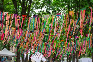Caddeyi süsleyen şenlikli renk saten kurdeleler. Düğün şenlikli dekorasyon, parkta ağaçlara asılı kurdeleler.