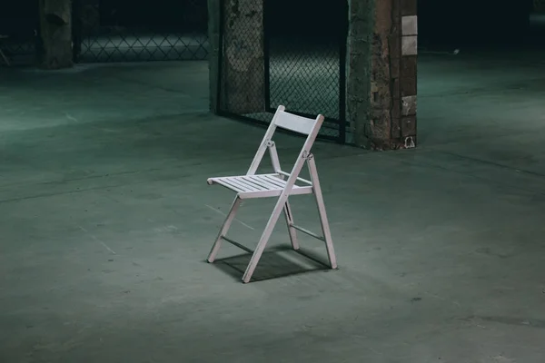 An empty chair in a dark room. A lonely object standing in empty concrete walls at dusk, a symbolism of loneliness of fear, mysticism, torture — Stock Photo, Image