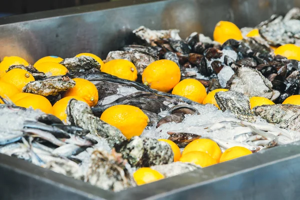 Een container met verse rauwe oesters en zeevruchten in het openluchtcafé, liggend op ijs met citroenen — Stockfoto