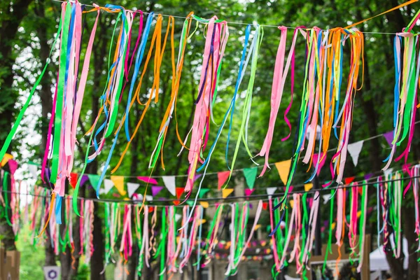 Festive color satin ribbons decorating the street. Wedding festive decoration, ribbons hanging on the trees in the park