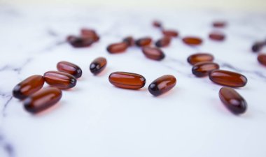 Bir sürü kahverengi hap, beyaz arka plandaki kapsüller. Tıbbi tema. Vitaminler, balık yağı. Spor ilaçları