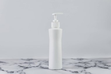 Boş nemlendirici kabı mermer masanın beyaz arka planında. Kozmetik plastik krem ya da losyon şişesi, etiketsiz boş..