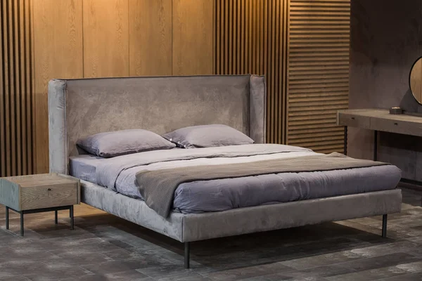 Elegante dormitorio en estilo loft, con tabiques de madera con listones, con un diseño de dormitorio suave y elegante. Cama doble con ropa de cama gris — Foto de Stock
