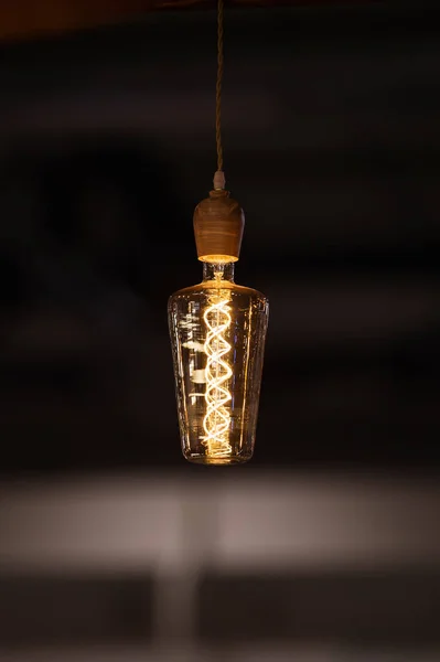 Lâmpada do tipo Edison incandescente vintage no fundo escuro. Lâmpada de design de forma incomum — Fotografia de Stock