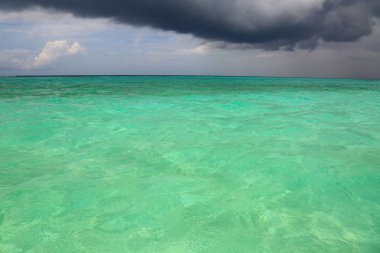 Hint Okyanusu ve koyu gri thunderclouds turkuaz su yüzeyi muhteşem doğa manzarası. Maldivler. Güzel arka planlar. 