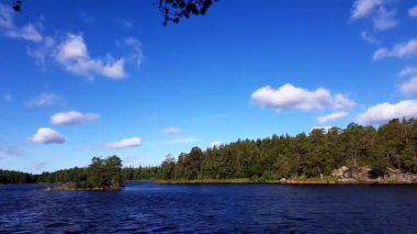 Zaman atlamalı. Muhteşem doğa manzara görünümünü bir rüzgarlı yaz gününde. Güzel, yeşil orman ve mavi gökyüzü göl ile beyaz bulutlar. İsveç, Europe. 