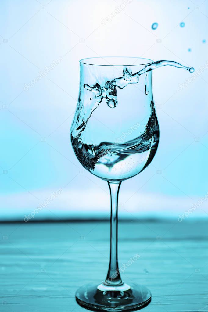 Close up view of splashing water in glass isolated. Blue / turquoise background. Beautiful backgrounds.