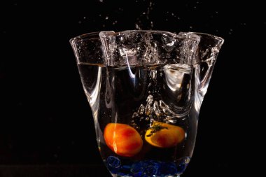 Su sıçramasına ve sarı meyve siyah arka plan üzerine vazo görünümünü kapatın. Güzel arka planlar.