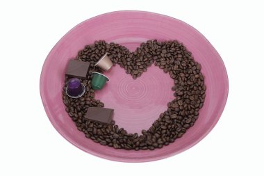 Coffee beans in shape of a heart with pieces of chocolate and coffee capsules isolated on white background with clipping path. Beautiful background.