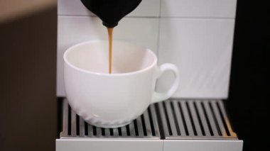  Kapsül kahve makinesinden beyaz fincana akan kahvenin yakın görüntüsü. Güzel arka planlar.