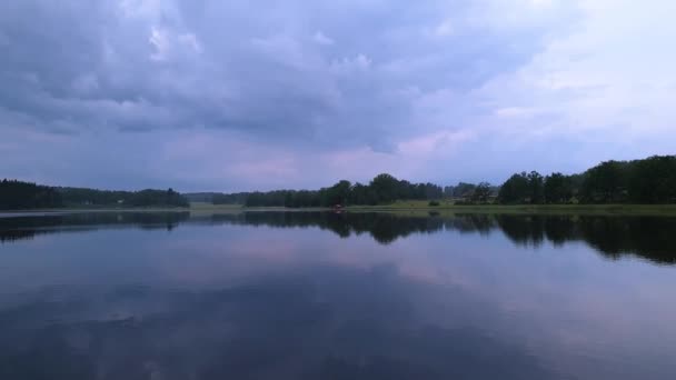 Vue magnifique sur le paysage naturel lors d'une soirée d'été calme. Rive du lac avec des arbres verts et des plantes se reflétant dans la surface de l'eau miroir cristalline. Ciel couvert de gros nuages de tonnerre. Beau dos 