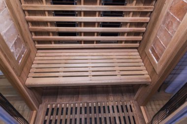 Kızıl ötesi sauna iç görünüş. Ahşap duvarlar, bank, seramik ısıtıcılar. Sağlıklı yaşam tarzı kavramı.