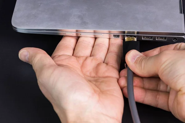 HDMI 'yi gümüş dizüstü bilgisayara bağlayan erkek eli görüntüsünü kapat. 
