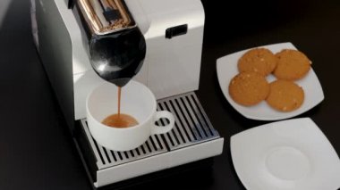 Kapsül kahve makinesinden beyaz fincana akan kahvenin yakın görüntüsü. Güzel arka planlar.