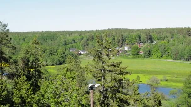 Gyönyörű kilátás nyílik a tájra. Hagyományos privát faházak a zöld erdők között. Kis folyó az aszfaltút mentén. Skandináv. Svédország. Európa.