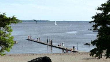 Göl manzarası muhteşem. Platformda su deneyen insanlar. Ufukta beyaz yelkenli göründü. İsveç. Avrupa. Uppsala. 06.11.2020.