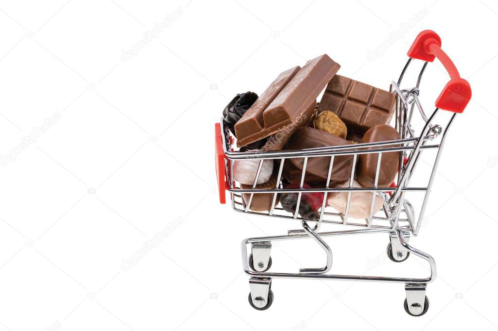Close up view of shopping cart filled with candies and chocolate. Unhealthy food. Health concept. 