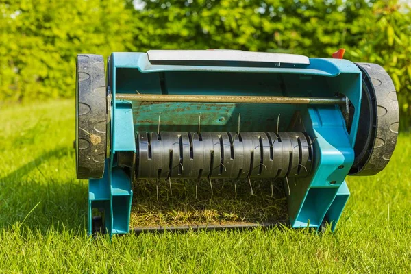 Yeşil çimenlikteki elektrikli çim makinesinin yakın görüntüsü izole edilmiş. Bahçe makineleri kavramı. 
