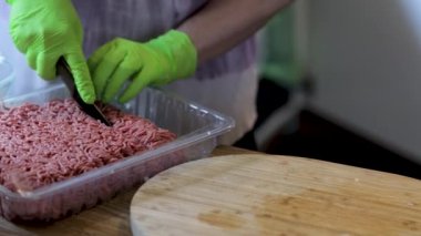 Yeşil eldivenli, kasede doğranmış etle çalışan kadınların yakın görüntüsü. Aşçılık konsepti arka planı.