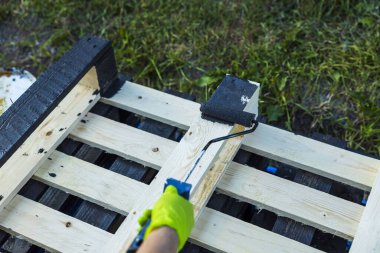 Elin boya silindiri tutuşu ve ahşap paleti özel siyah ağaç yağı ile tedavi edişinin yakın görüntüsü.