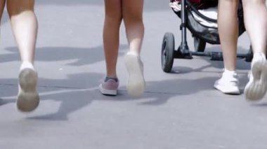Yürüyen insan bacakları manzarası. Çocuklar, yazlık ayakkabıların içinde yetişkinler yaz günü parkta yürüyor..