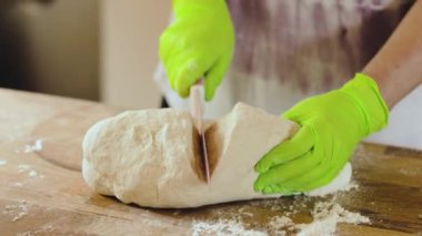Yeşil eldivenli, hamur yoğuran kadın ellerini yakından izle. Ev yapımı gıda konsepti.