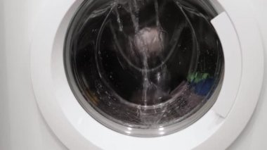 Çamaşır makinesinde dönen çamaşırların kapalı görüntüsü izole edilmiş. Ev aletleri kavramı.