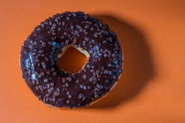 Turuncu arka planda izole edilmiş çikolatalı çöreğin yakın görüntüsü. Yiyecek ve içecek konsepti.