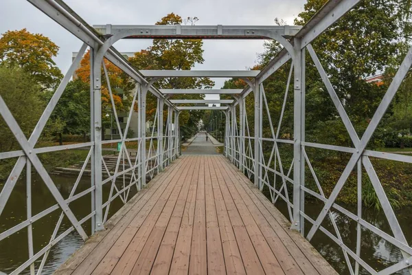 美しい秋の都市景観 緑の自然景観を背景に川の水を渡る金属製の橋 — ストック写真