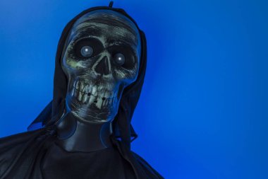 Siyah arka plandaki mavi ışıklı iskelet kafasının yakın görüntüsü. Cadılar Bayramı konsepti.