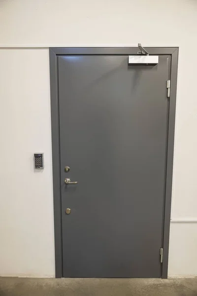 Close up view of grey metal door with digital code lockand extra heavy aluminum commercial door closer. Security concept.