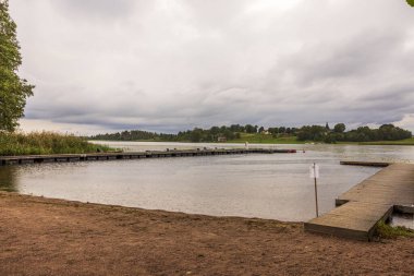 Yağmur sırasında tekneler ve kumsallar için iskele olan güzel bir sonbahar gölü manzarası. İsveç.