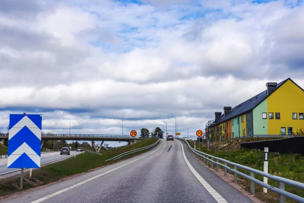 Arka planda renkli konutlara karşı arabalı otoyol ve hız sınırı tabelası. 