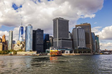 East River 'daki Orange Staten Island Feribotu, Manhattan' daki gökdelenlerin ve bulutlu gökyüzünün arka planına karşı. - New York. ABD. 