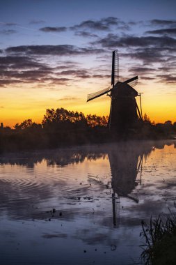 Bir yel değirmeni sıcak ve kırmızı renk gündoğumu Hazerswoude-Dorp Köyü, Hollanda, silüeti