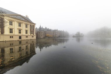 Puslu sabah Hofvijver üzerinde Hollanda Parlamentosu yansıyan Lahey, sakin su
