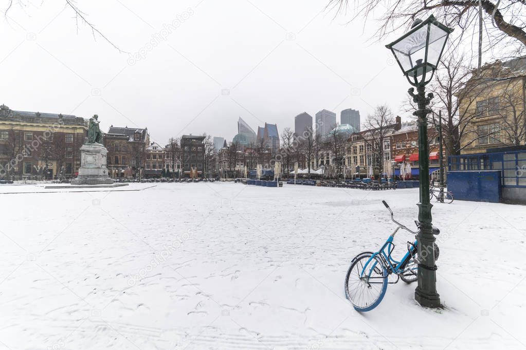 Bicycle locked with the lamp post at the central place covered by snow, Plein (Dutch), usually crowded with people getting diner and drink during the sunset and warm weather in The Hague, Netherlands