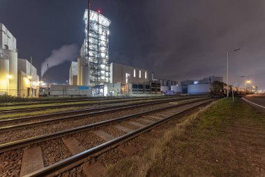 Demiryolunun hammaddeyi taşıyıp götürdüğü bir sanayi bölgesinin gece görüşü