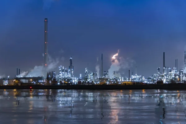 Hollanda Rotterdam 'da gün batımında alevler içindeki rafinerilerin ve bacalarının yansıması.