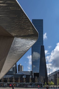 Rotterdam, 13 Nisan 2019 - Rotterdam tren istasyonu yapısı modern binaya işaret ediyor ve güneşli bir gün ışıkları altında yolcuları bekleyen bir tramvay