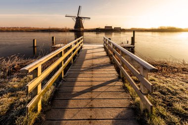 Kinderdijk değirmeninin önündeki sıcak sabah güneşinin altındaki tekne platformu.