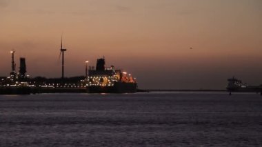 Günbatımında uluslararası nakliye limanındaki kargo gemisi konteynırlarını parlak dalga yansımalı stratocumulus bulutları ve Rotterdam, Hollanda 'da kırmızı canlı gökyüzü ile dolduruyor.