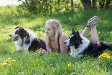 İki sınır Collies köpekler arasında açık havada yatan gülümseyen genç sarışın kadın yan görünüm. Kadın ve köpek ileriye baktığımızda.