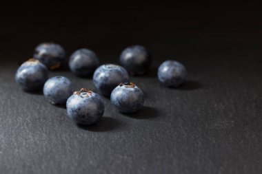 Grup dokuz taze Kanadalı yaban mersini bir karanlık taş masanın üzerinde yatan. Karanlık bir arka plan üzerinde her şey.