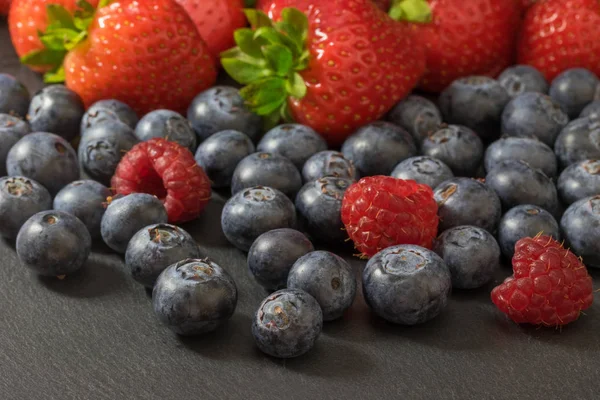 Mix Van Aardbeien Bosbessen Frambozen Ligt Een Donkere Stenen Tafel — Stockfoto