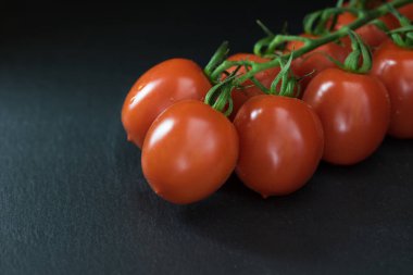 Düşük anahtar çalılar domates siyah taş masanın üzerinde yatan bir yarısı ile vurdu. Metninizi fotoğrafı için yer.